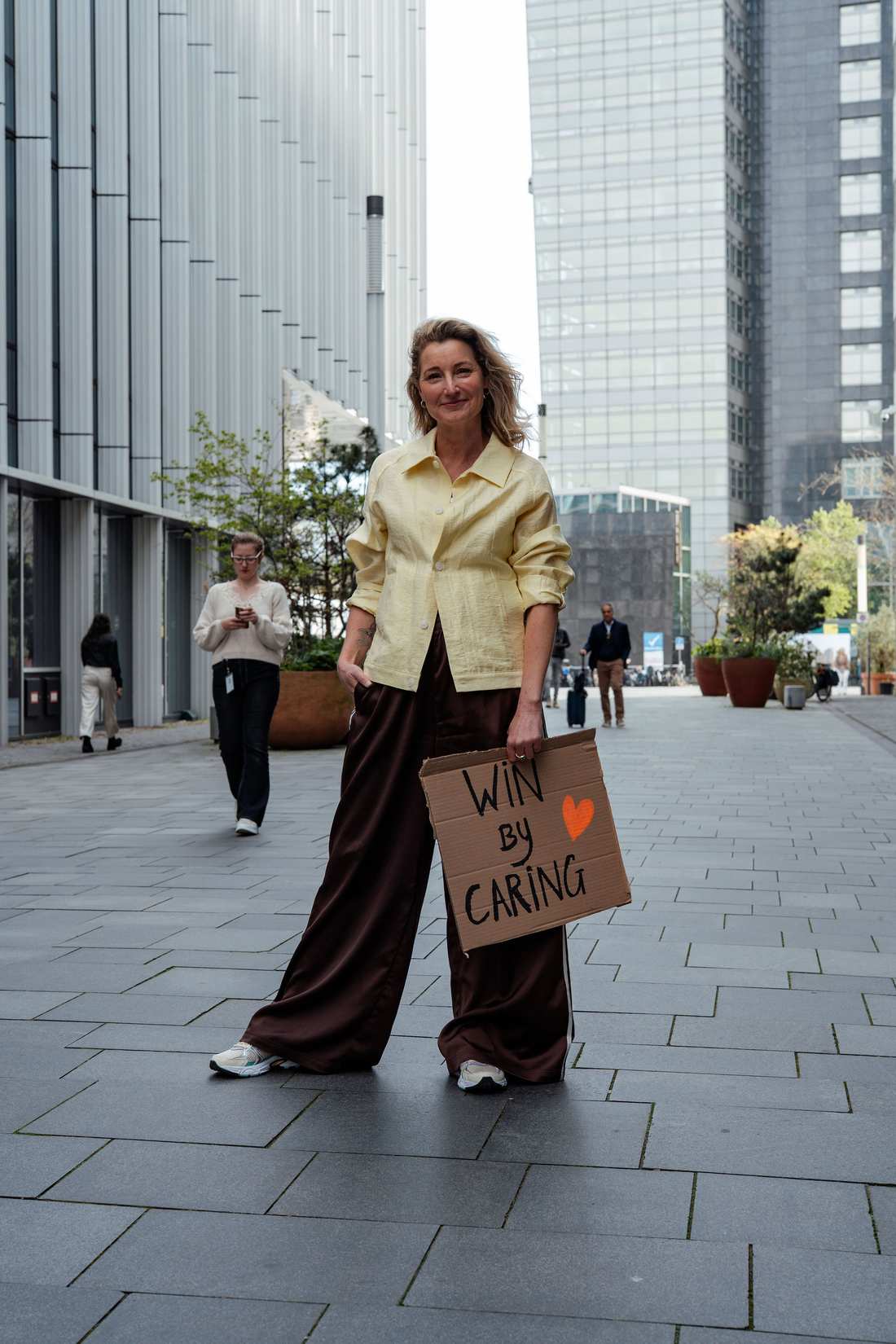 Dian tussen kantoorgebouwen met een bord: Win by caring