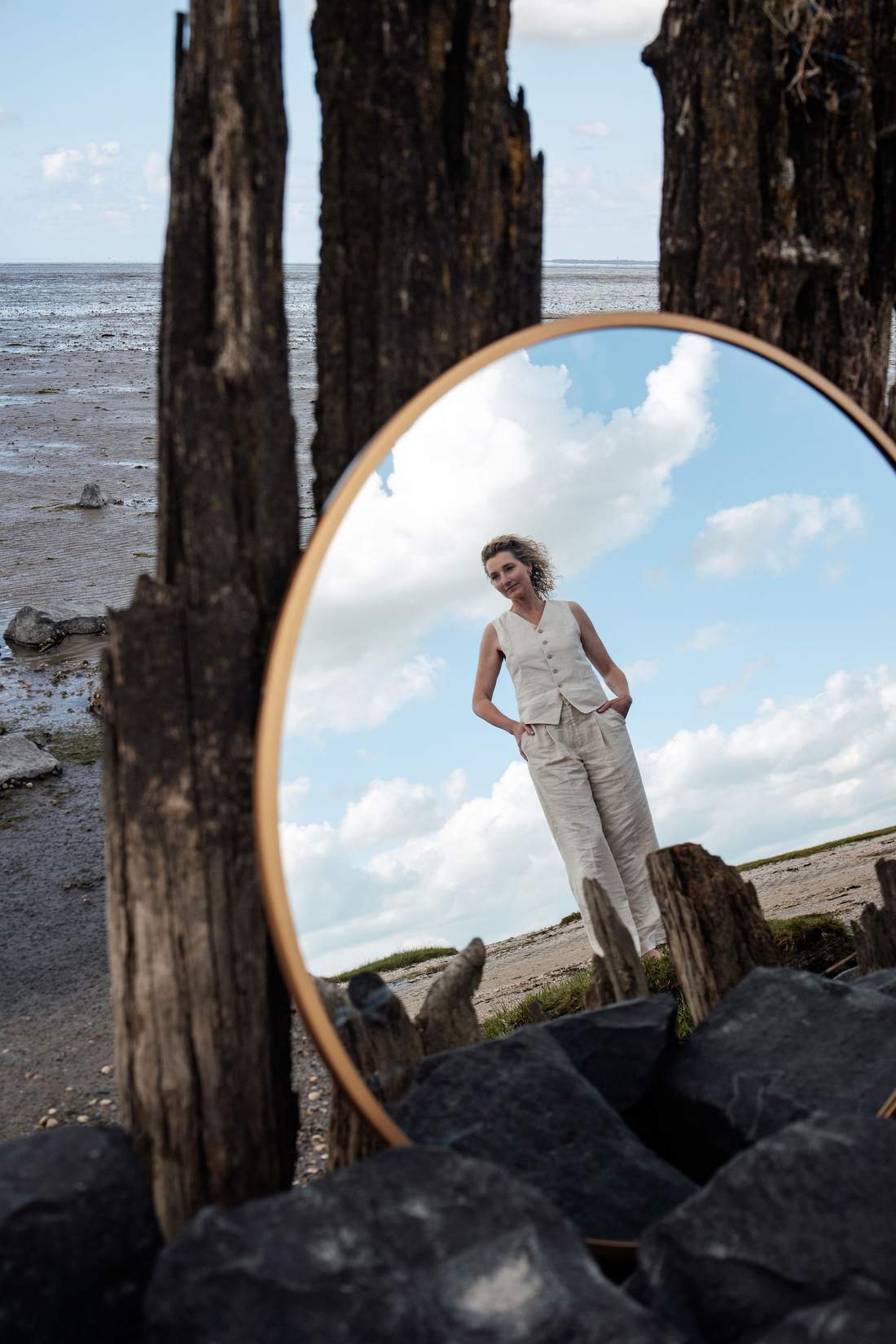 Dian weerspiegeld in een ronde spiegel tussen houten palen aan het water