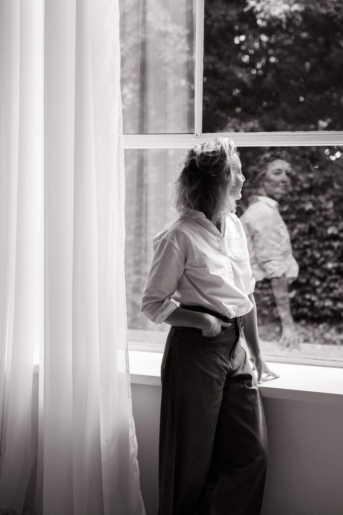 Dian kijkt naar buiten bij het open raam